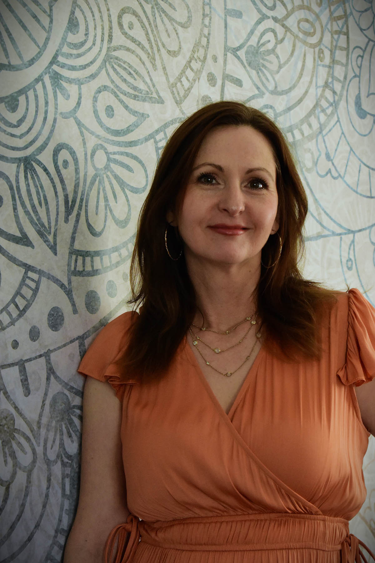 Simona smiling at camera, leaning against wall inside yoga studio